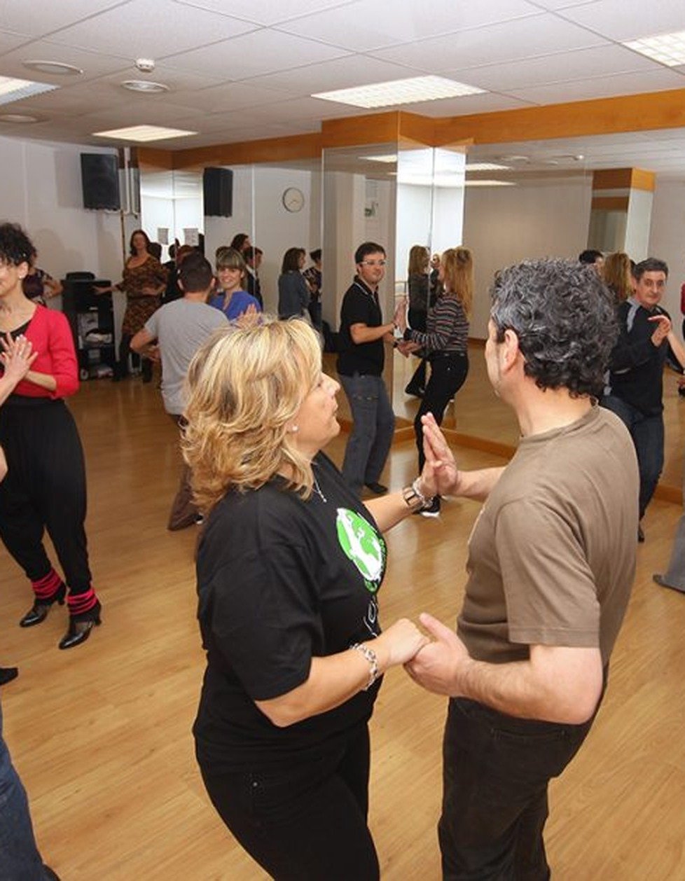 Grupo bailando en parejas en una sala con espejos